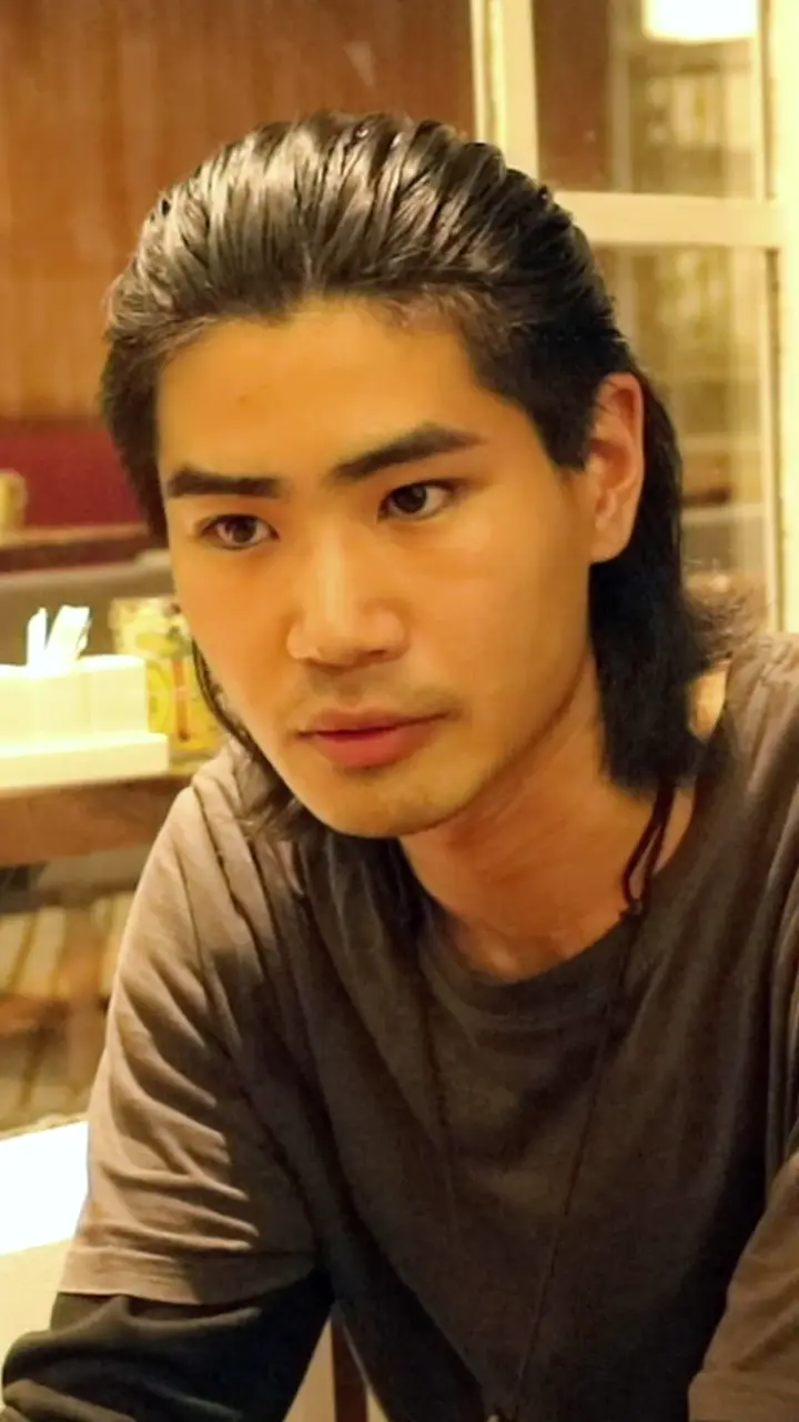 カフェで、まっすぐ前を見て話すバズさん